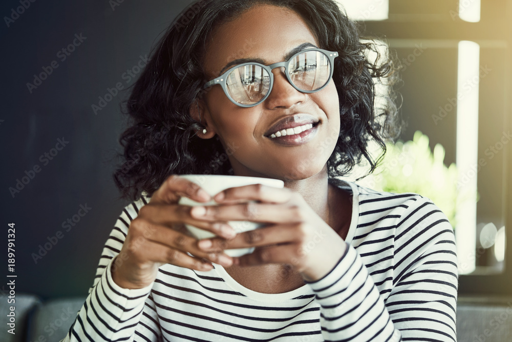 Smiling young African woman enjoying coffee in a cafe