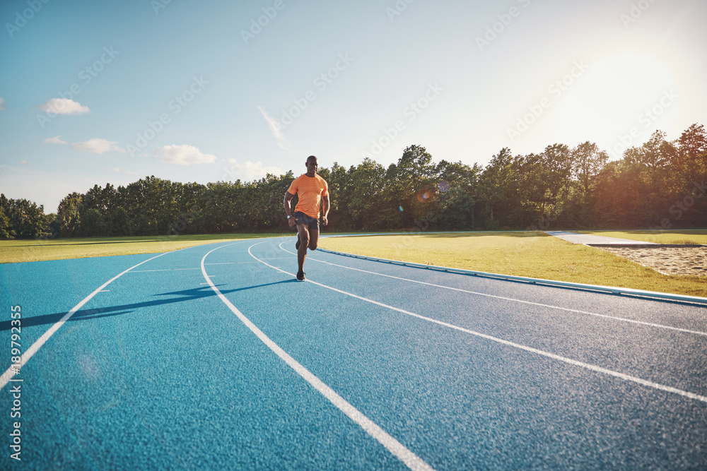 Fit young athlete sprinting alone down an outdoor track