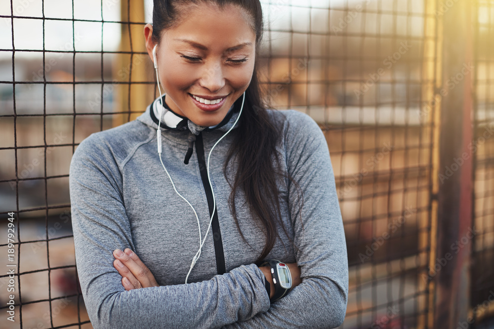 Sporty young Asian woman standing with her arms crossed outside