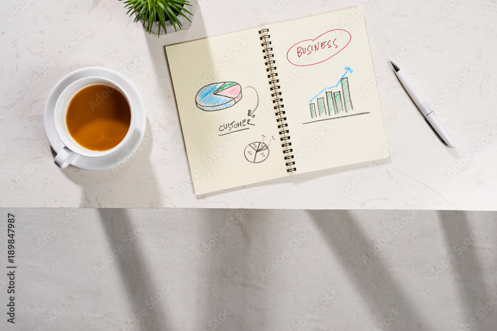 Minimal styled flat lay table with open notebook, croissant and tea.