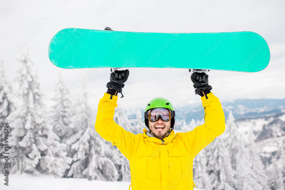 一个穿着冬季运动服的男人在山上拿着滑雪板的肖像