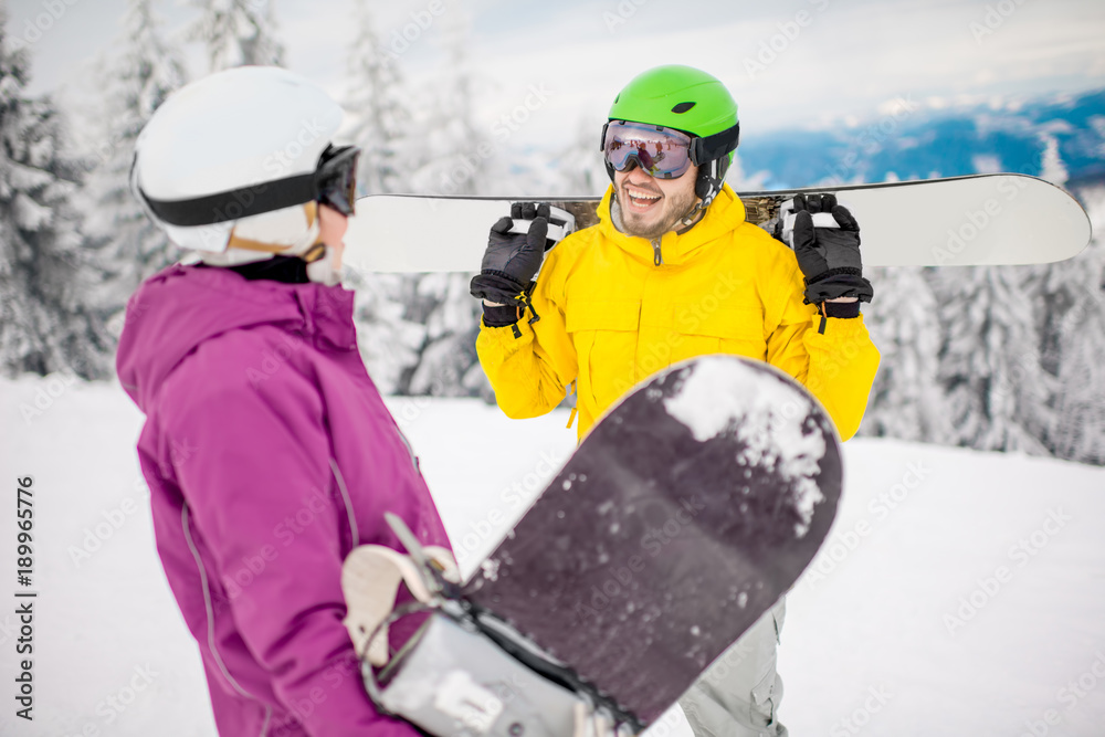 Young couple in winter sports clothes talking together with snowboards during the winter vacation on