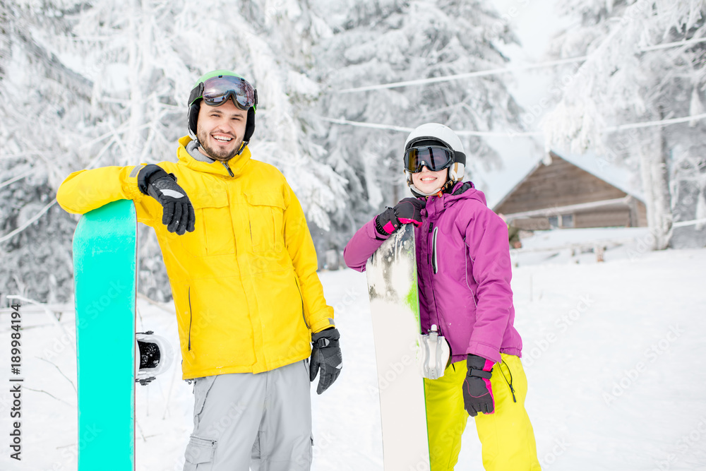 Young couple standing in winter sports clothes during the winter vacation on the snowy mountains