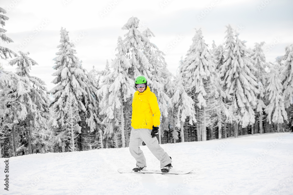 一名身穿五颜六色运动服的男子在有美丽树木的雪山上滑雪