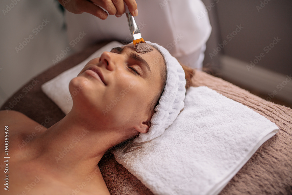 Woman getting facial nourishing mask at spa salon