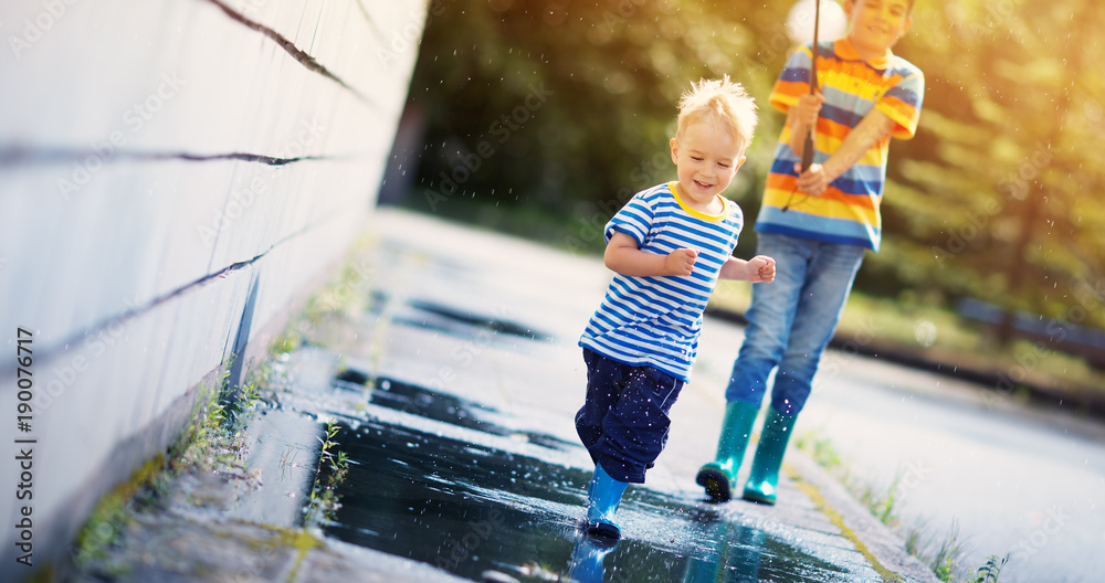 Children walking in wellies in puddle on rainy weather