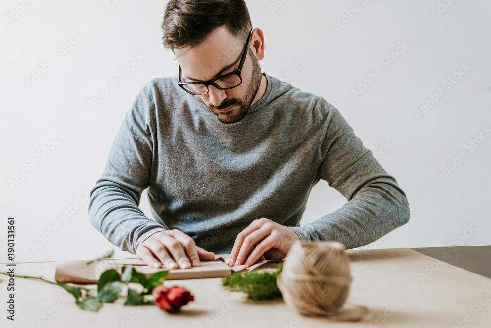 帅气男士用环保包装纸包装情人节礼物。