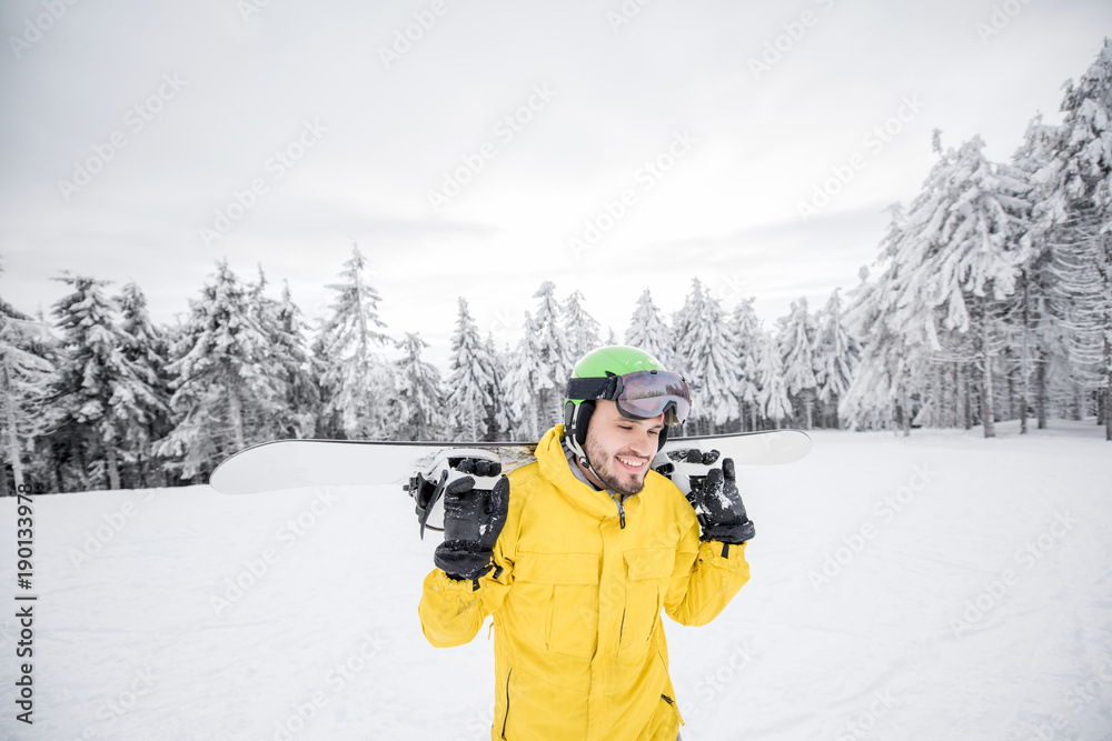 身穿黄色冬装的男子在雪山上滑雪板行走