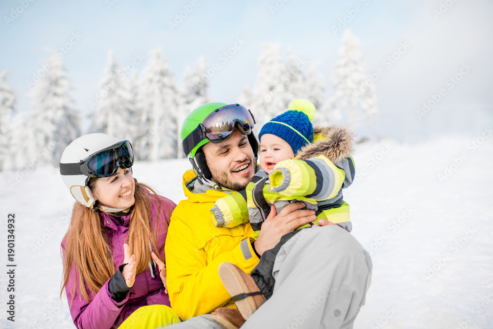 寒假期间，美丽的雪地上，一个带着男婴的幸福家庭的画像