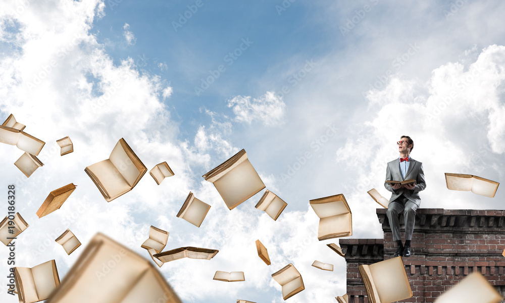 Young businessman or student studying the science and books flying around