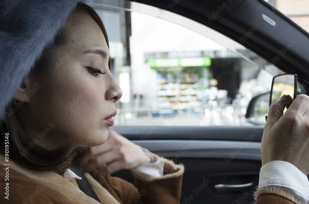 女性は車の助手席で鏡を見ている