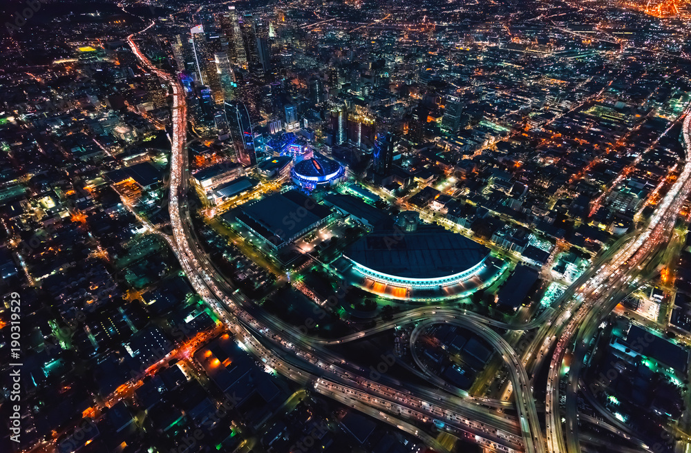 Aerial view of Downtown Los Angeles at night with young woman holding out a smartphone in her hand