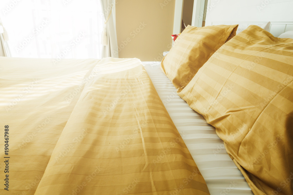 Bed maid-up with clean white  pattern pillows and bed sheets in beauty room. Close-up. Lens flair in