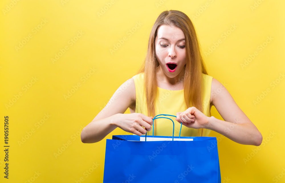 Young woman holding a shopping bag on a yellow background