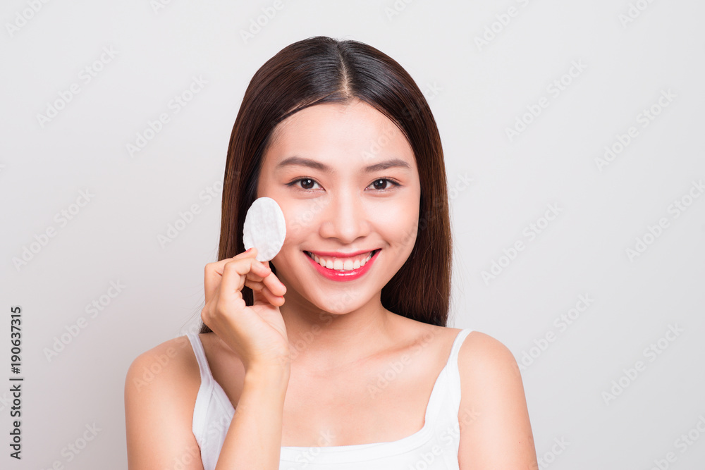 Happy smiling beautiful young asian woman cleaning skin by cotton pad.