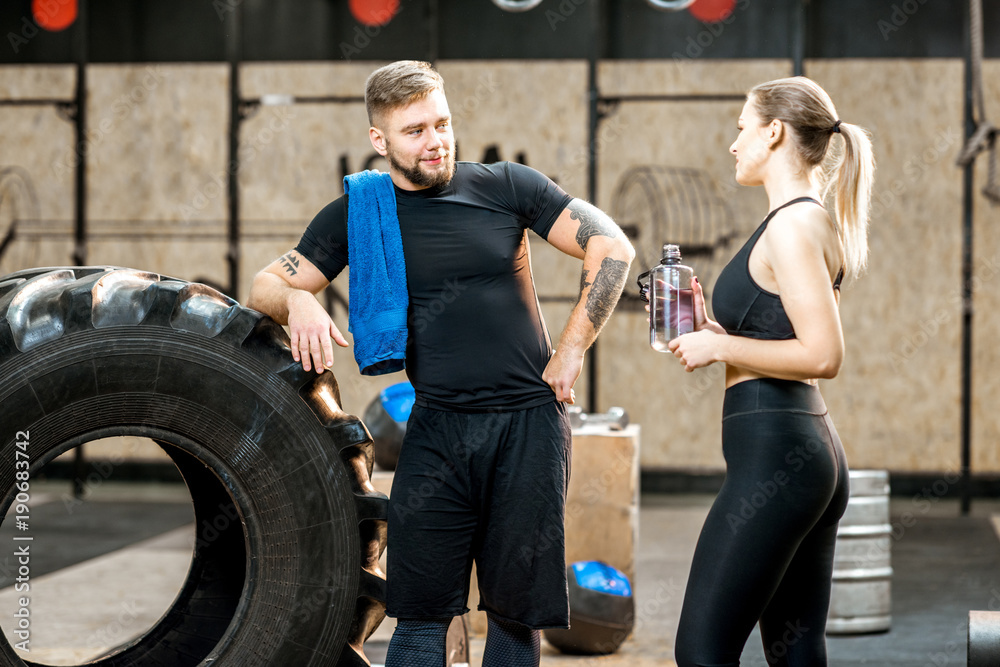 训练结束后休息时，一对年轻的运动情侣在crossfit健身房里一起聊天