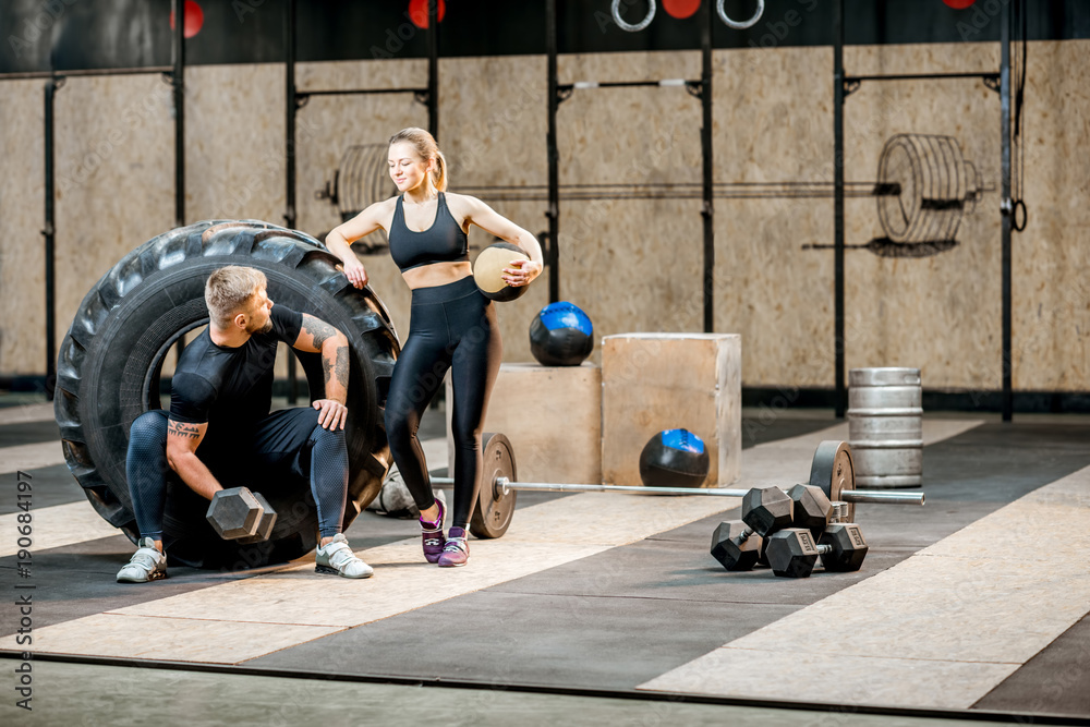 一对年轻的运动情侣在crossfit健身房的大轮胎附近进行运动训练后休息