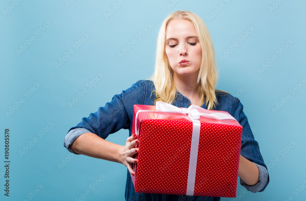 Happy young woman holding a gift box on a blue background