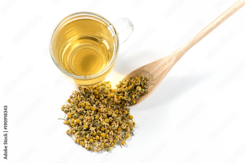 Dry Camomile Tea in a spoon on white background.