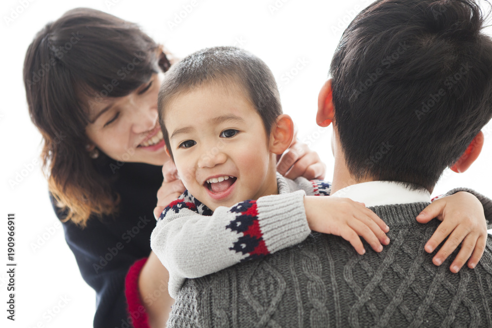 お父さんに抱きついて甘えている男の子。お母さんも子どもを可愛がっている。