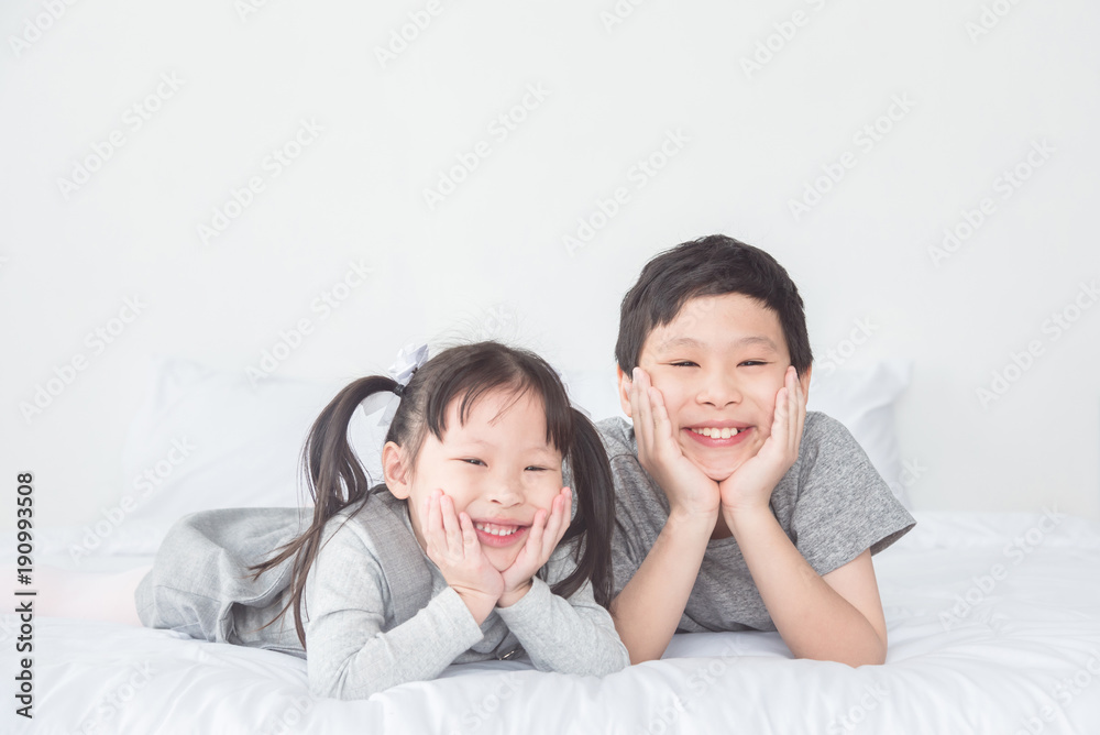 Asian boy and girl lying on bed and smile at camera