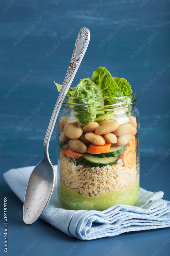 vegan couscous salad in mason jar with beans cucumber carrot and avocado dressing