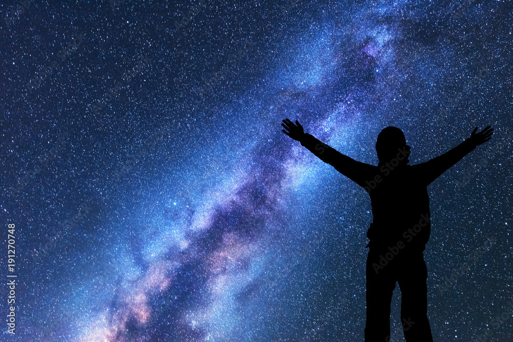 Milky Way with silhouette of a happy woman with backpack and raised up arms at night. Space backgrou