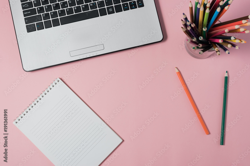 Minimal workplace with laptop and blank notepad on pink background. Top view. Flat lay.