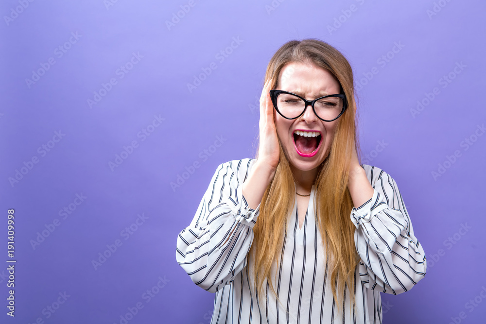 年轻女子在坚实的背景上挡住耳朵