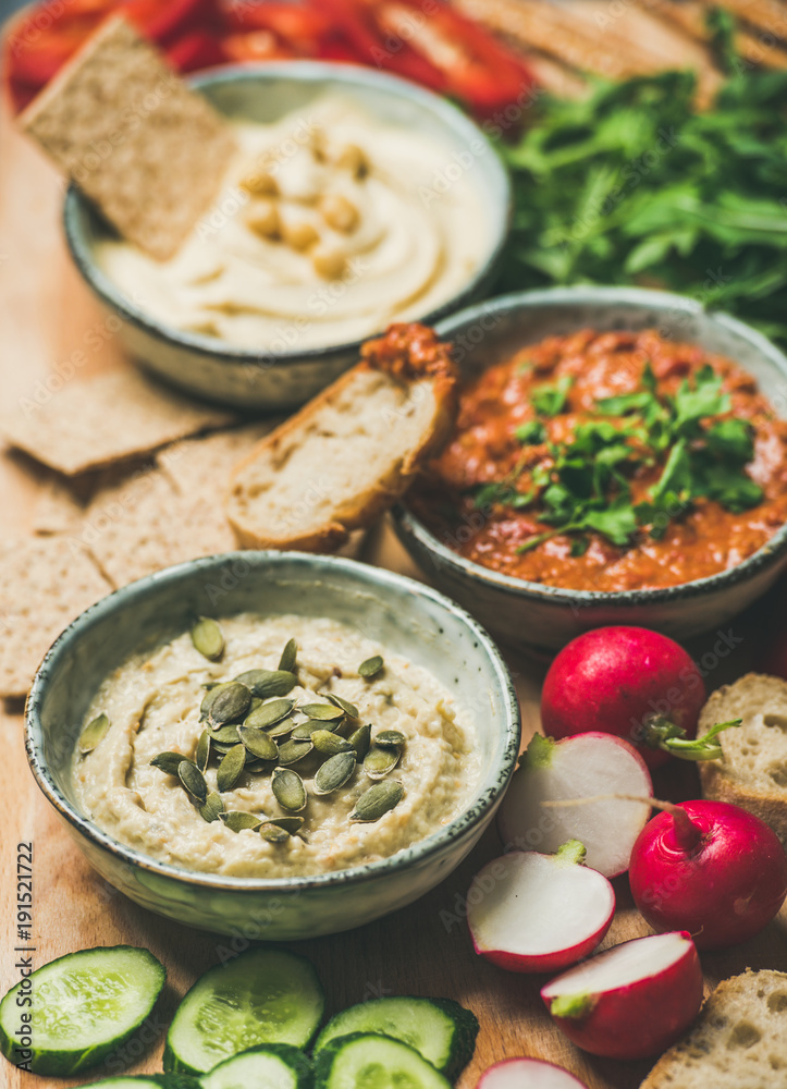 Vegan snack board. Various Vegetarian dips hummus, babaganush and muhammara with crackers, bread and