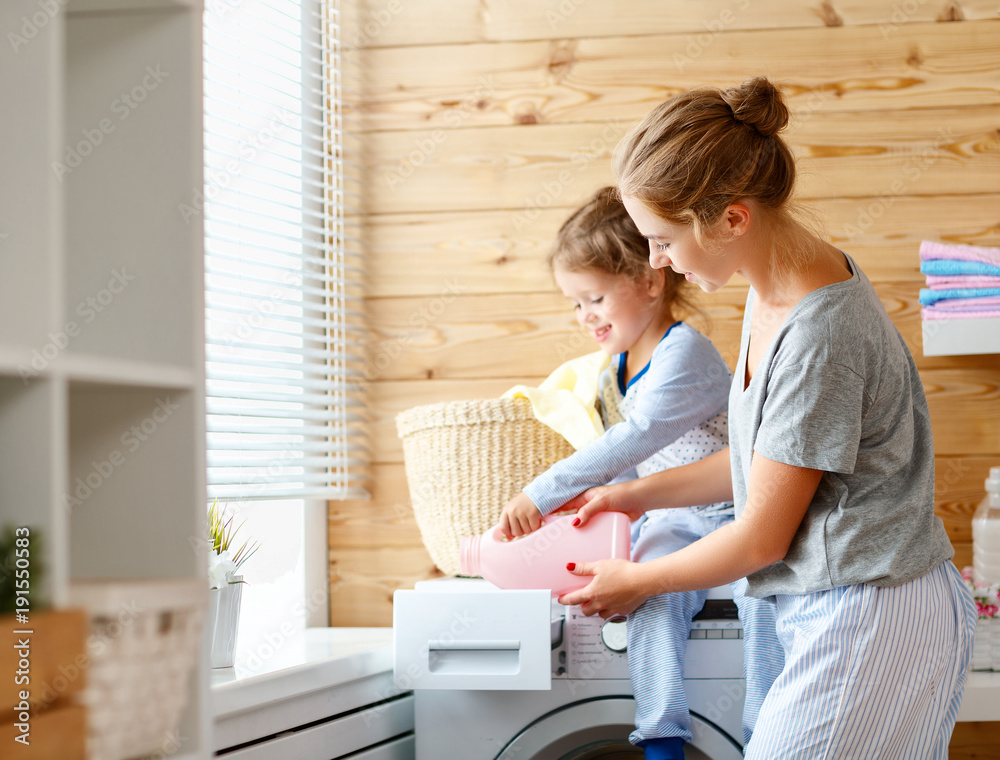 Happy family mother housewife and child   in laundry with washing machine