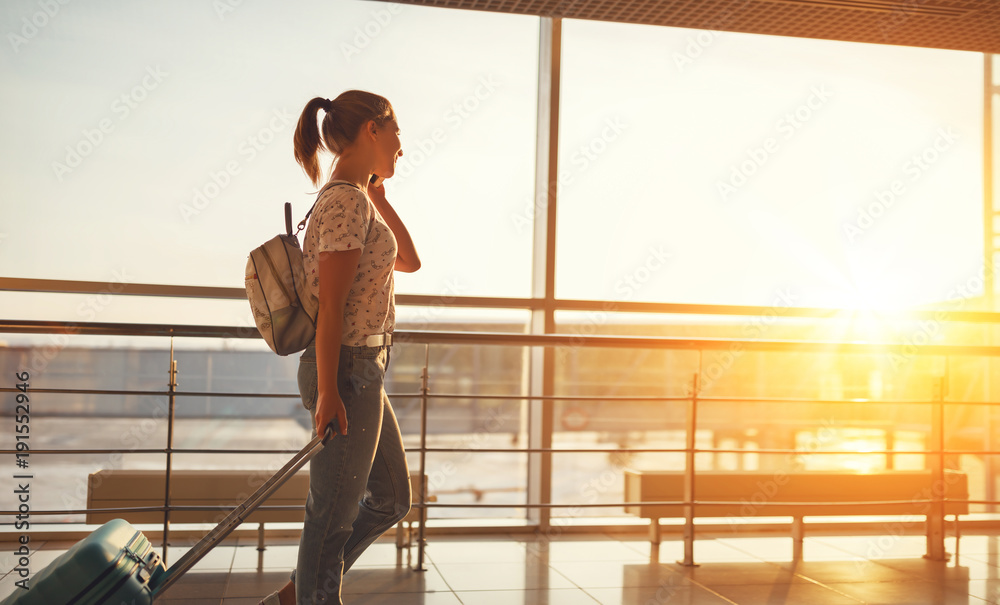 woman talking on phone waiting for flying at airport  at window with suitcase  .