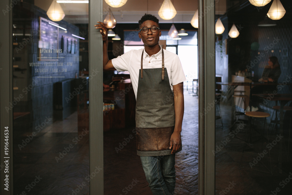 Young entrepreneur standing in front of his coffee shop