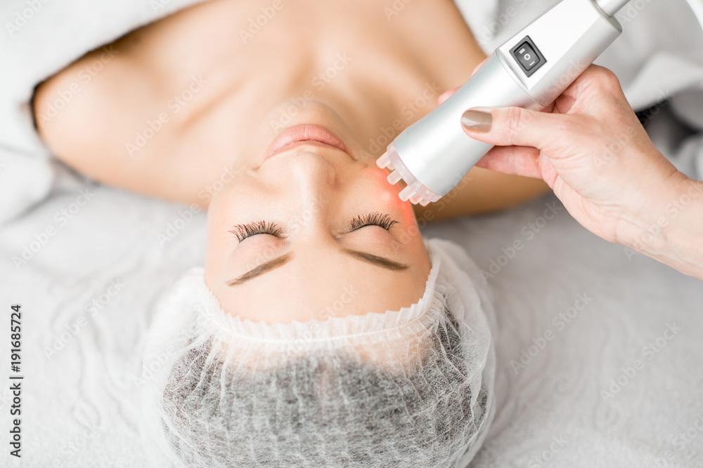 Young woman during a facial massage with professional tool at the medical center