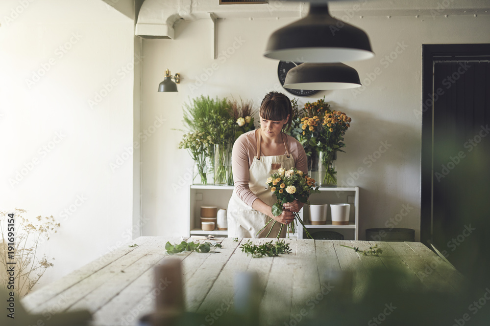 Young florist working in her flower ship making a bouquet