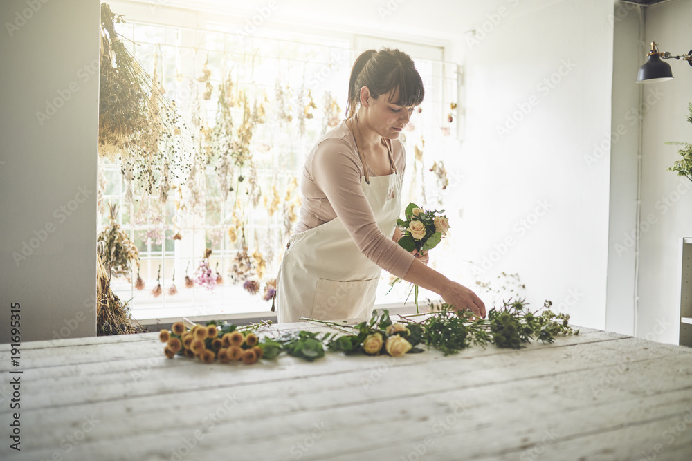 年轻的花艺师在花店的桌子旁工作