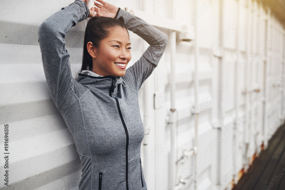 Smiling Asian woman in sportswear standing outside before a jog