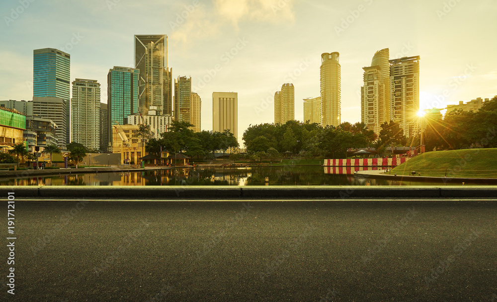 沥青路一侧，有美丽的吉隆坡城市海滨天际线。日出场景。