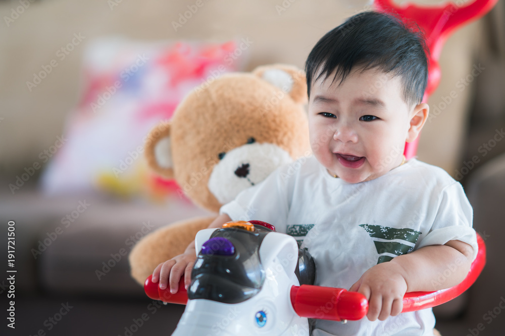 Asian baby and teddy bear play a bycycle toy togather