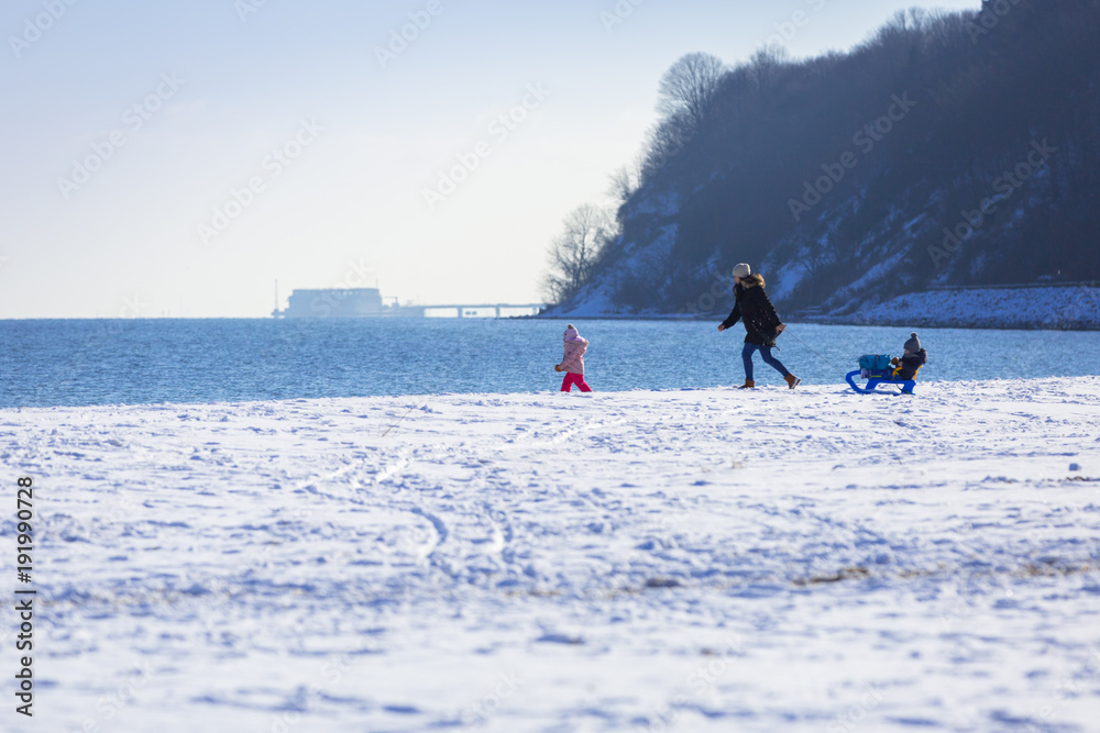 波兰，带着双胞胎的母亲在雪地海滩上散步