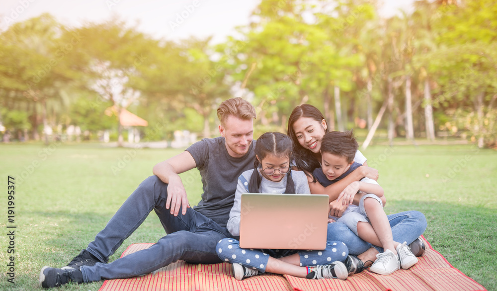 Modern family using laptop while resting in park