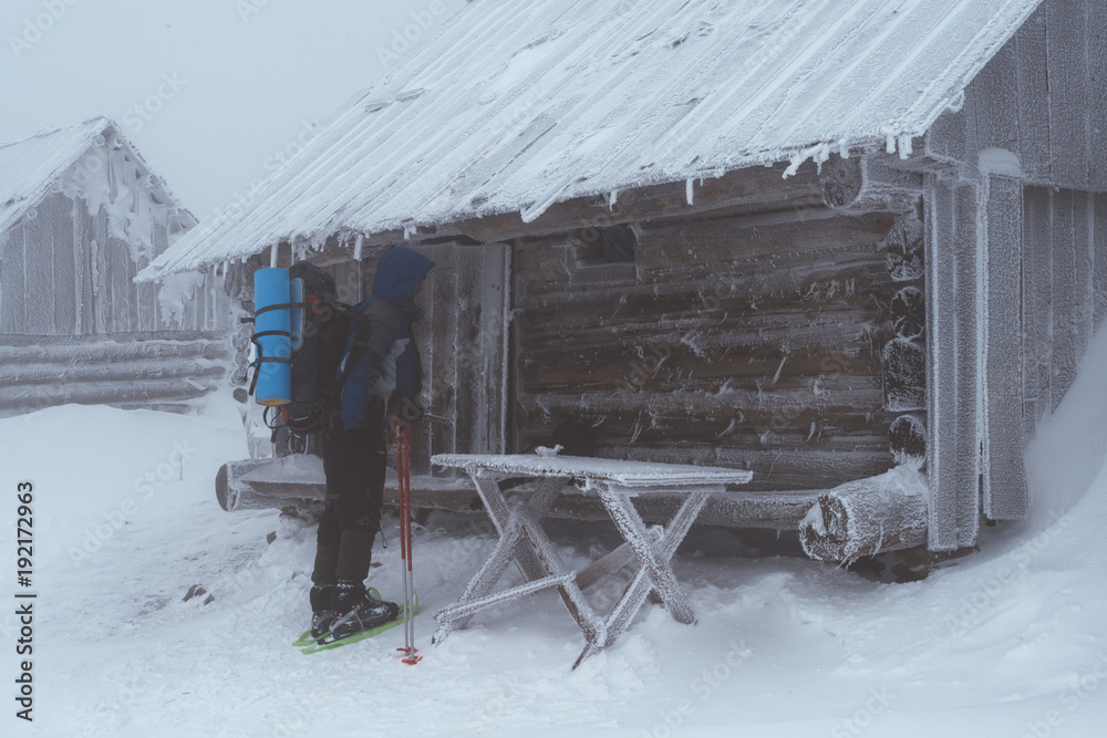 冬天独自一人背着背包在高山上旅行。雪地里的冰冻木屋