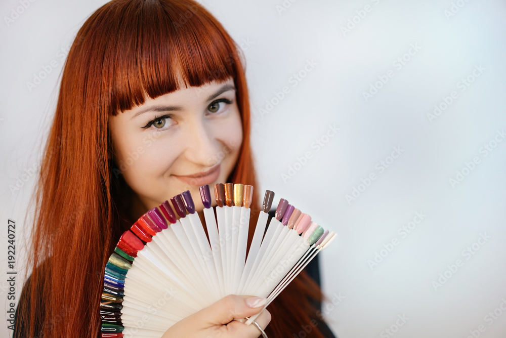 Girl with a beautiful manicure, holding in her hands samples of manicure. Portrait of a woman with r