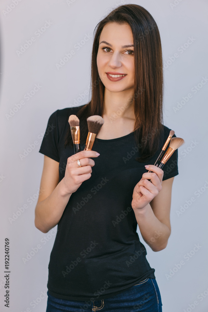 Portrait of beautiful woman with makeup brushes. Isolated on white