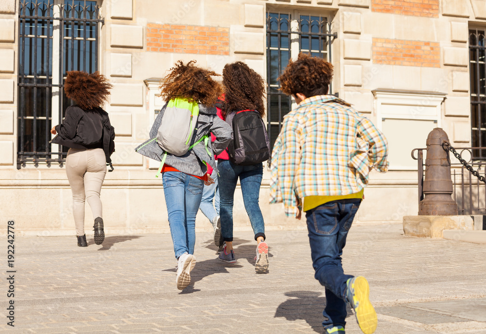 Big group of kids with backpacks running to school