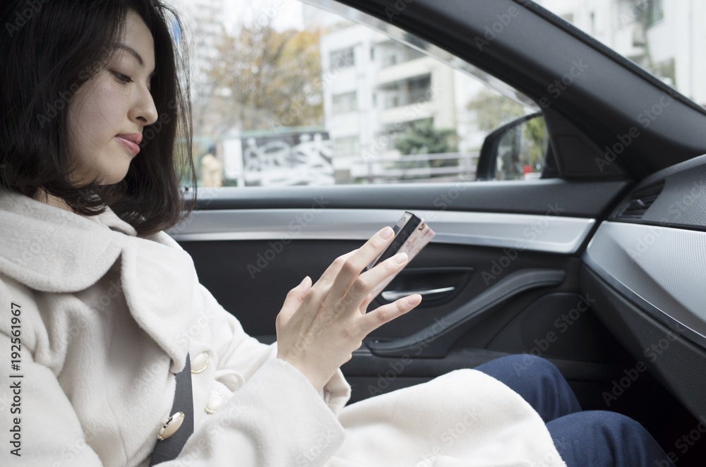 運転中に助手席でスマートフォンをいじる女性。