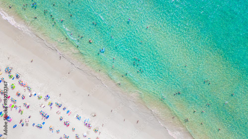 Aerial view Tropical white sand beach with azure clear water, umbrella and lush greenery. Top view. 