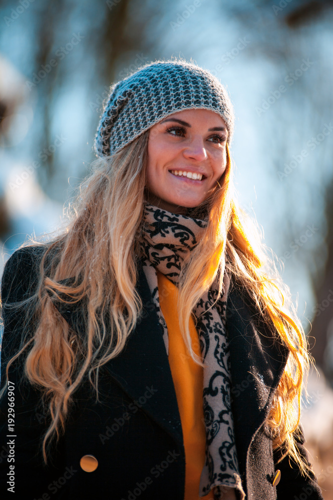 Smiling young woman during walk in the winter park at sunny day