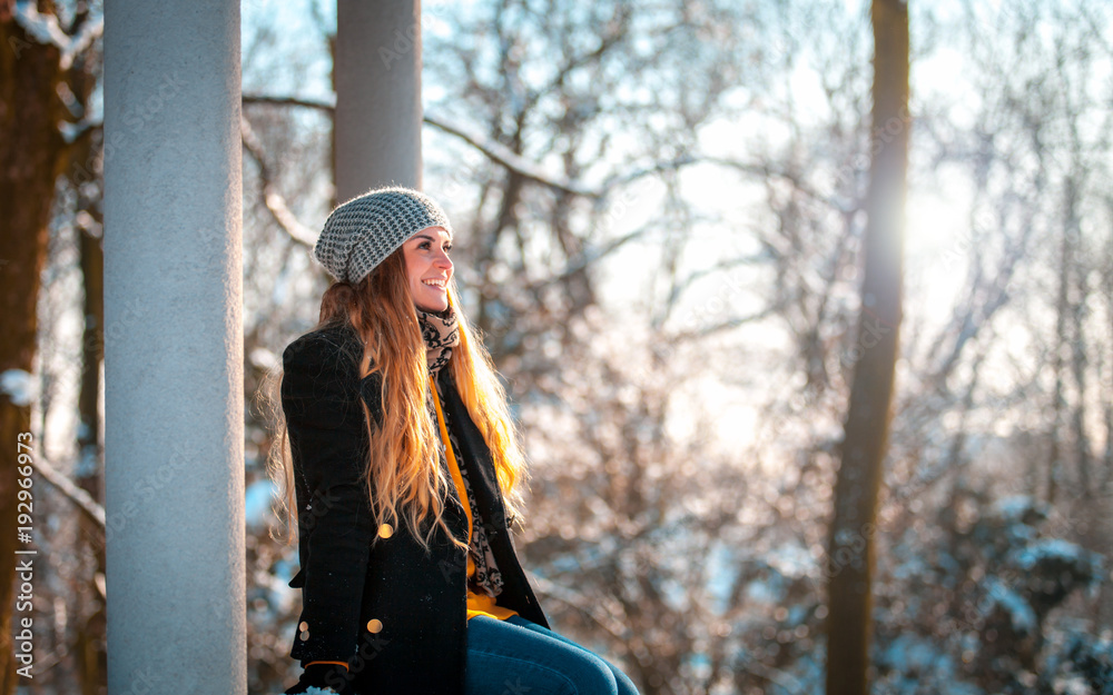 Smiling young woman during walk in the winter park at sunny day