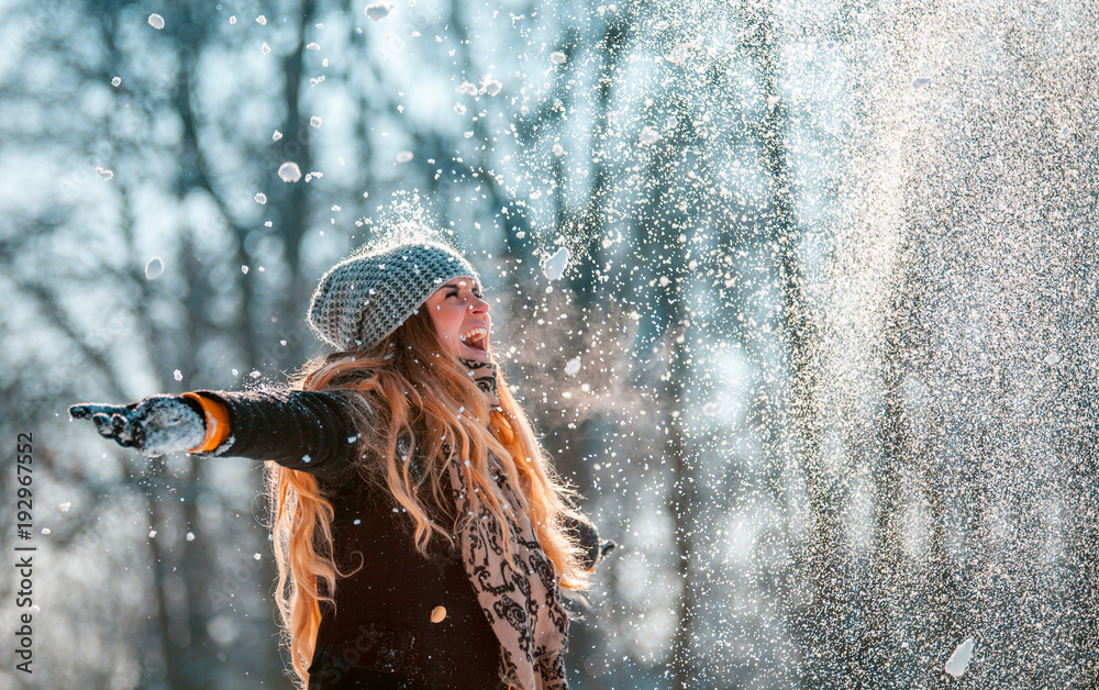 阳光明媚的冬日，微笑的女人向空中扔雪